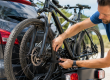 Homme en train de sangler des vélos sur un porte-vélos à l’arrière d’une voiture